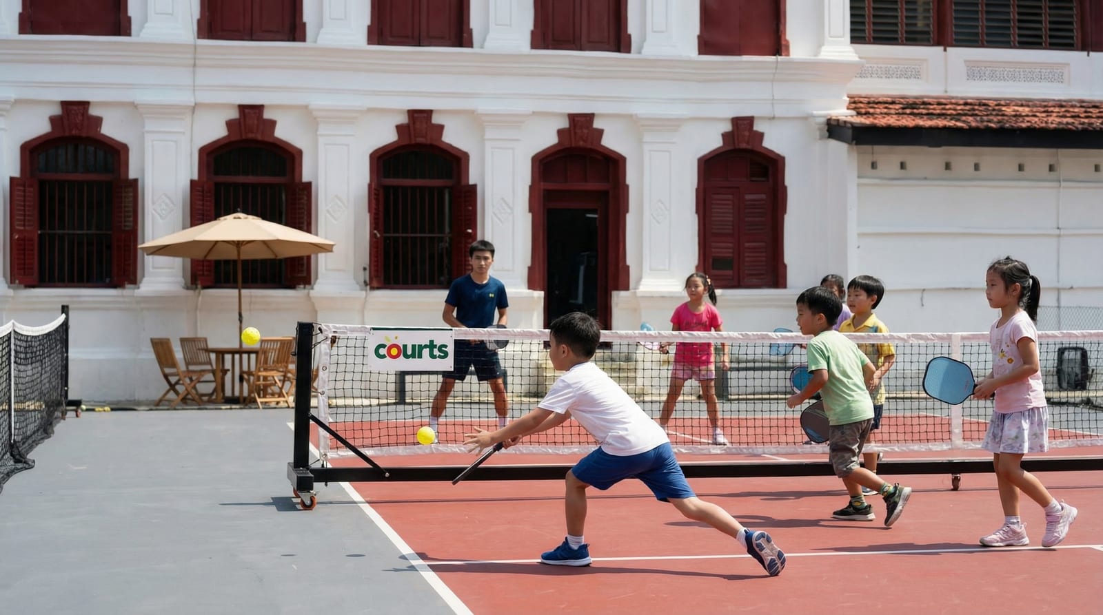 Group of children playing pickleball on court with a coach